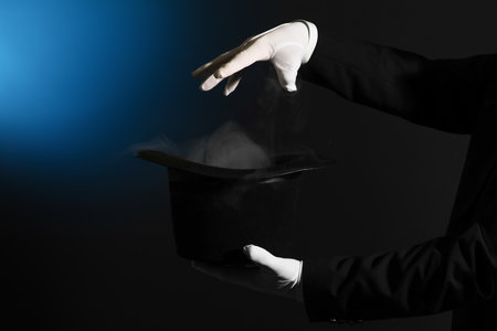 Male magician's hands and hat with smoke on dark backgroundの写真素材