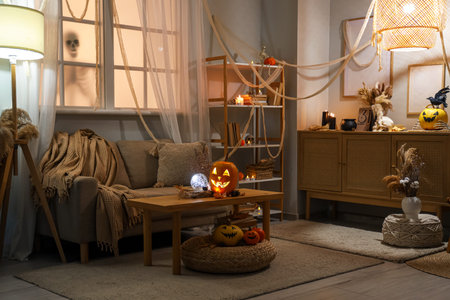 Interior of living room decorated for Halloween with sofa, pumpkins and glowing lamps in eveningの写真素材