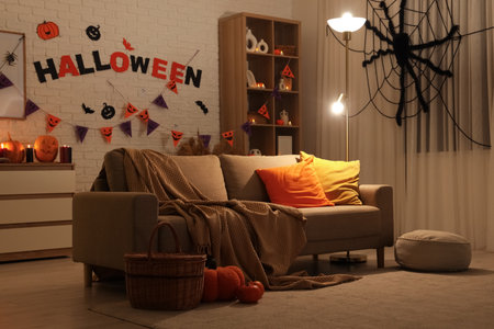 Interior of living room decorated for Halloween with sofa, shelf unit and glowing lamp in eveningの写真素材
