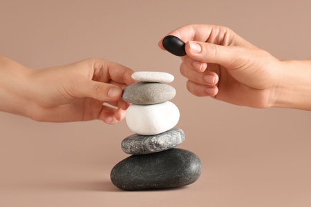 Hands putting pebbles in stack on beige background. Zen conceptの写真素材