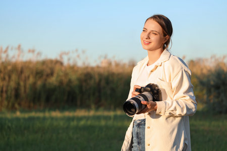 Smiling female photographer with camera in park