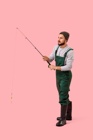 Handsome young man with fishing rod on pink backgroundの写真素材