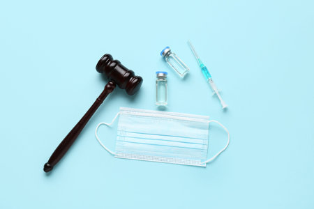 Judge gavel, ampules, syringe and medical mask on blue background. Concept of health care reform