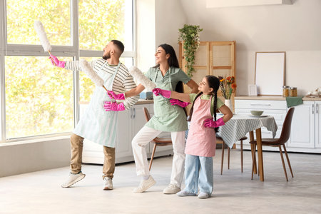 Happy family with pp-dusters dancing while cleaning in kitchenの写真素材