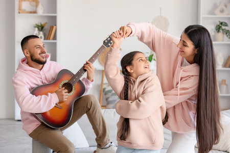 Happy parents with guitar and their little daughter dancing at homeの写真素材