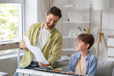 Private music teacher with note sheets giving synthesizer lessons to boy at homeの写真素材