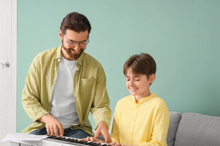 Private music teacher giving synthesizer lessons to boy in roomの写真素材