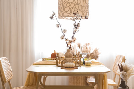 Autumn table setting with pumpkins, cotton flowers and candles in roomの写真素材