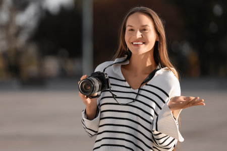 Young happy female photographer with camera on streetの写真素材