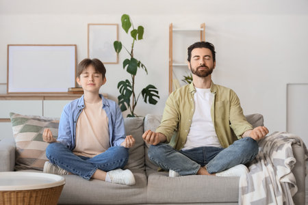 Father with his son meditating on sofa at home. Zen conceptの写真素材