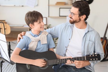 Cute boy learning guitar with private music teacher in roomの写真素材