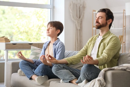 Father with his son meditating on sofa at home. Zen conceptの写真素材