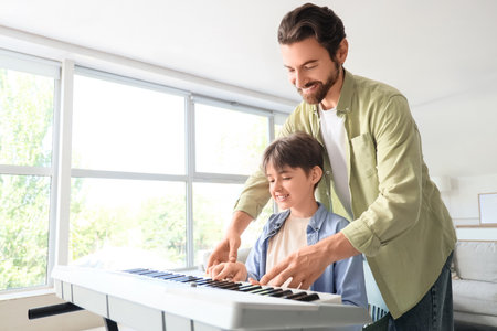 Private music teacher giving synthesizer lessons to boy at homeの写真素材