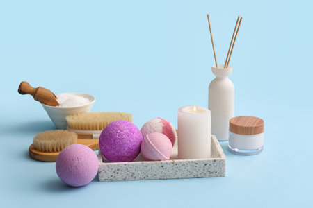 Composition with tray, bath bombs, burning candle and jar of cosmetic product on blue backgroundの写真素材