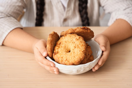 Little girl with bowl of cookies at table in kitchen, closeupの写真素材
