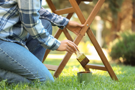 Woman painting wooden table in gardenの写真素材