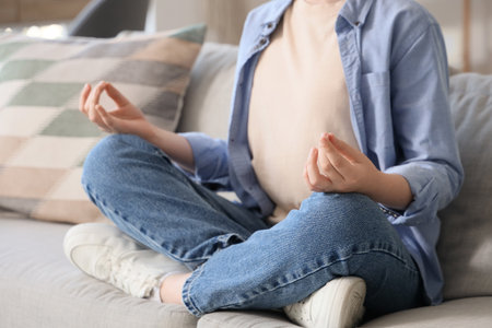Cute boy meditating on sofa at home, closeup. Zen conceptの写真素材