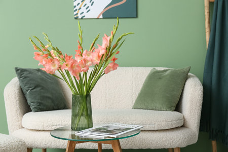 Vase with beautiful gladiolus flowers on table in interior of living roomの写真素材