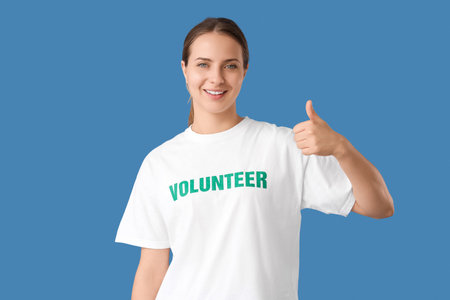 Female volunteer showing thumb-up on blue backgroundの写真素材