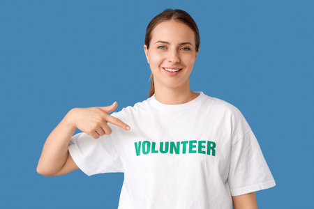 Female volunteer pointing at her t-shirt on blue backgroundの写真素材