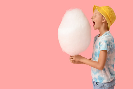Teen boy with cotton candy on pink backgroundの写真素材
