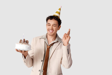 Young man with Birthday cake making wish on white backgroundの写真素材