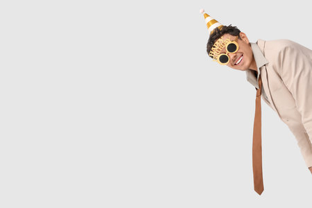 Happy young man in party hat with Birthday eyeglasses on white backgroundの写真素材