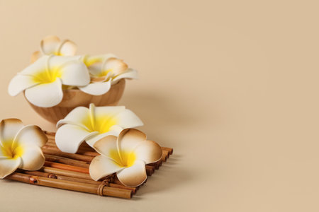 Beautiful plumeria flowers with bamboo mat on beige backgroundの写真素材