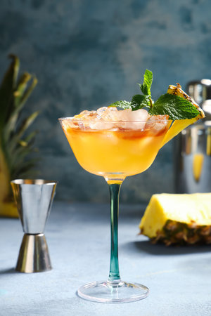 Glass of tasty Mai Tai cocktail garnished with mint and pineapple on blue backgroundの写真素材