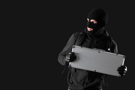 Male thief with case on black backgroundの写真素材