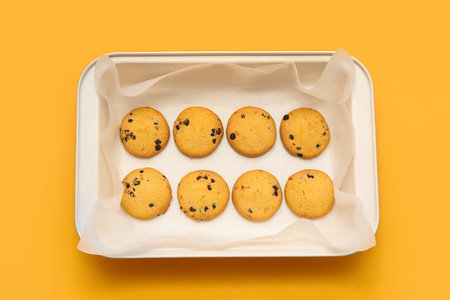 Baking tray with tasty cookies on yellow background
