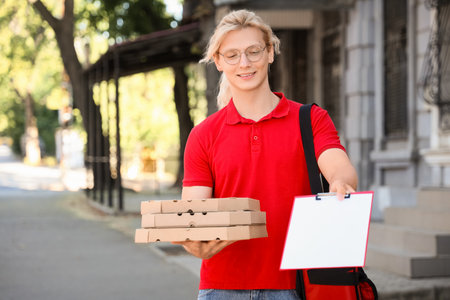 Male courier with pizza boxes and clipboard on streetの写真素材