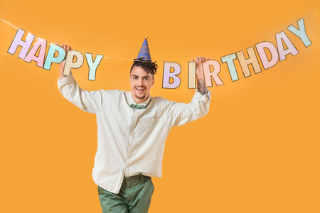 Happy young man celebrating Birthday on yellow backgroundの写真素材