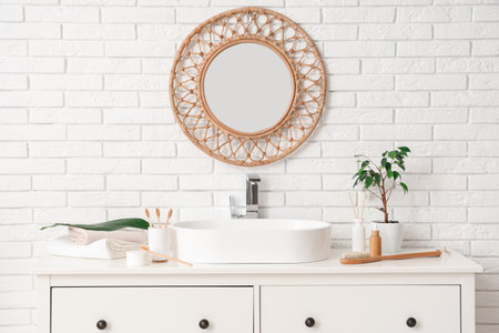 Interior of light bathroom with sink, toothbrushes and toiletry on chest of drawersの写真素材