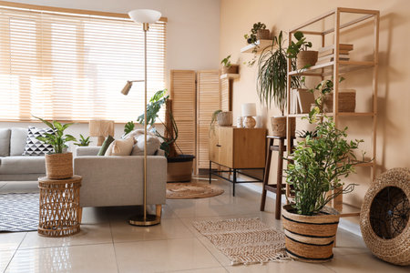 Gray sofas, floor lamp and wicker baskets with houseplants near window in interior of living room