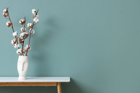 Vase with cotton flowers on table near green wall in living room, closeupの写真素材