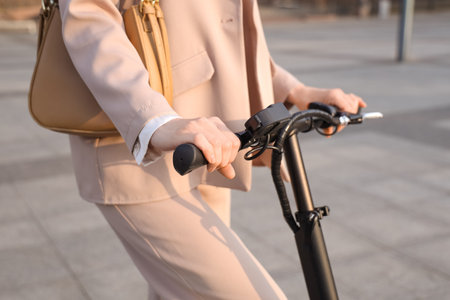 Young businesswoman riding electric scooter on street, closeup