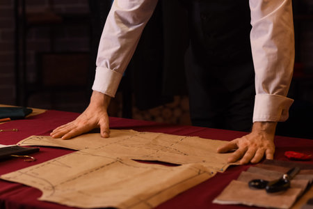 Male tailor working with pattern in atelier at night, closeup