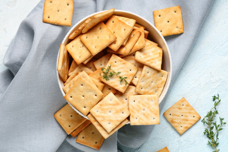 Composition with bowl of tasty crackers and thyme twigs on blue grunge background, closeupの写真素材