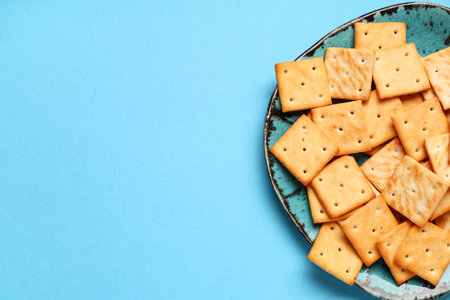 Plate with tasty crackers on blue background, closeupの写真素材