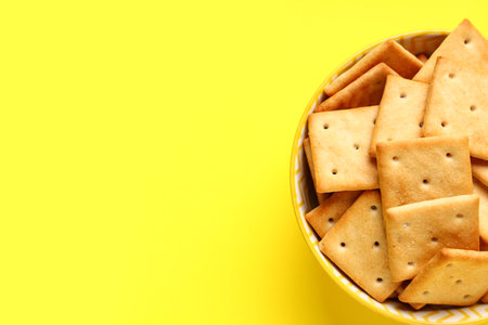 Bowl with tasty crackers on yellow background, closeupの写真素材