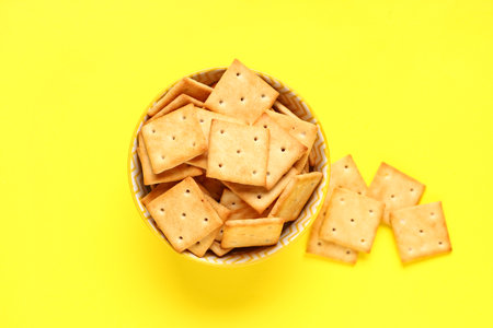 Bowl with tasty crackers on yellow background, closeupの写真素材