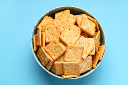 Bowl with tasty crackers on blue background, closeupの写真素材