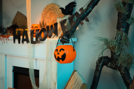Interior of festive living room with Spooky Halloween monster, garland and autumn decorations on...