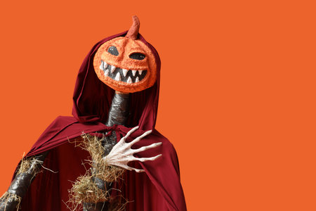 Spooky Halloween scarecrow in cape on orange backgroundの写真素材