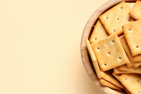 Wooden bowl with tasty crackers on beige background, closeupの写真素材