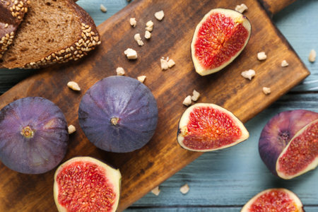 Composition with cutting board, fresh ripe figs and toast on blue wooden background, closeupの写真素材