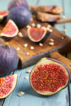 Composition with cutting board, fresh ripe figs and scattered nuts on blue wooden background, closeupの写真素材