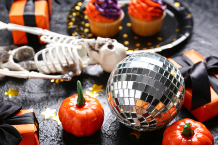Disco ball with gift boxes, skeleton and Halloween decor on black grunge backgroundの写真素材