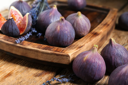 Board with fresh ripe figs and lavender flowers on wooden background, closeupの写真素材